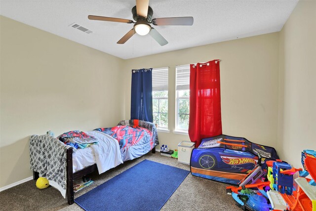 carpeted bedroom featuring ceiling fan and a textured ceiling