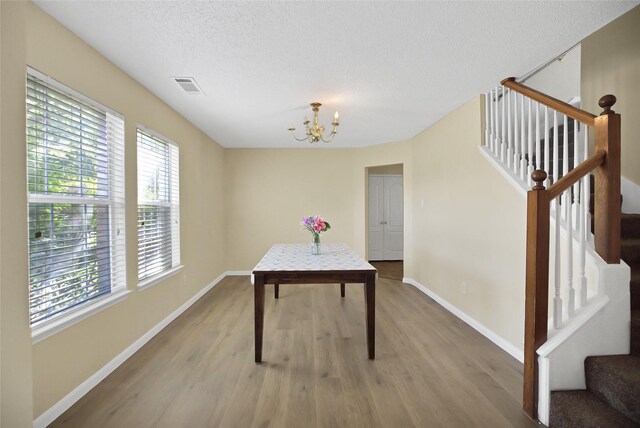 office space with a notable chandelier, light hardwood / wood-style floors, and a textured ceiling