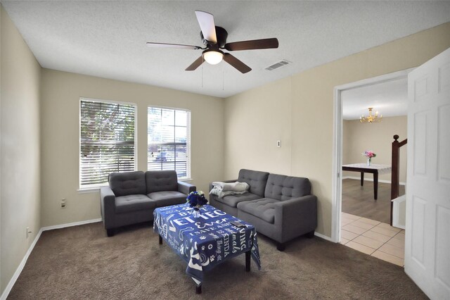 living room featuring ceiling fan with notable chandelier, carpet, and a textured ceiling