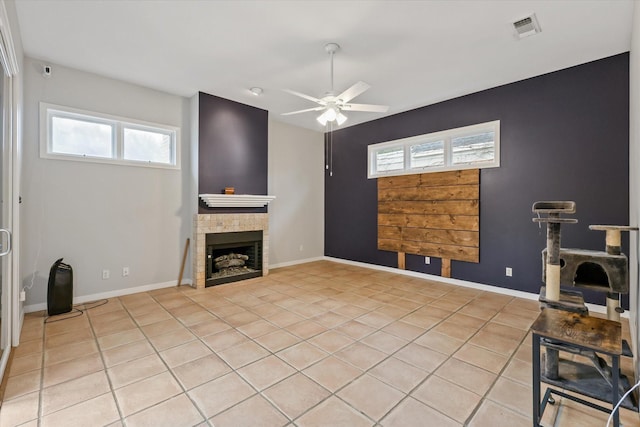 unfurnished living room featuring ceiling fan, light tile patterned flooring, and a fireplace