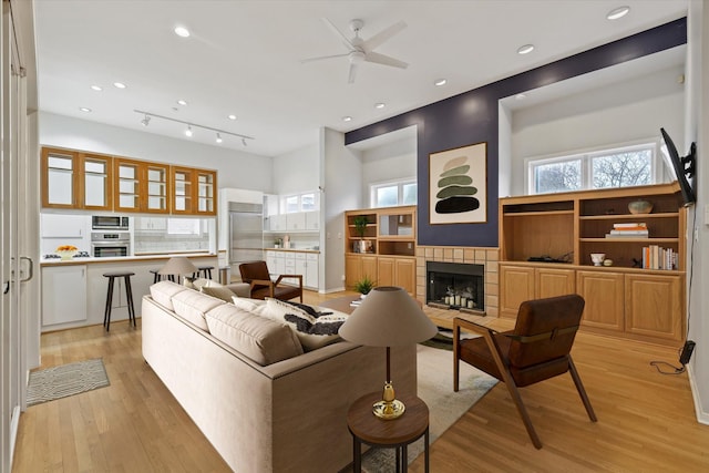 living room with light hardwood / wood-style flooring, a fireplace, and ceiling fan