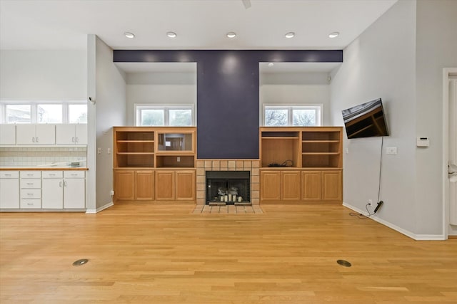 unfurnished living room with plenty of natural light, a tile fireplace, and light wood-type flooring