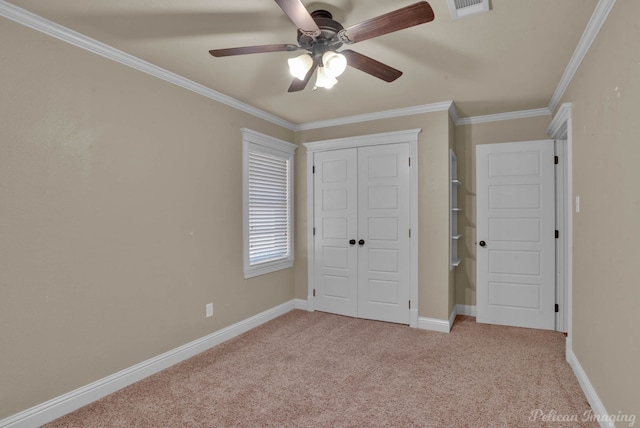 unfurnished bedroom with ceiling fan, a closet, light carpet, and crown molding