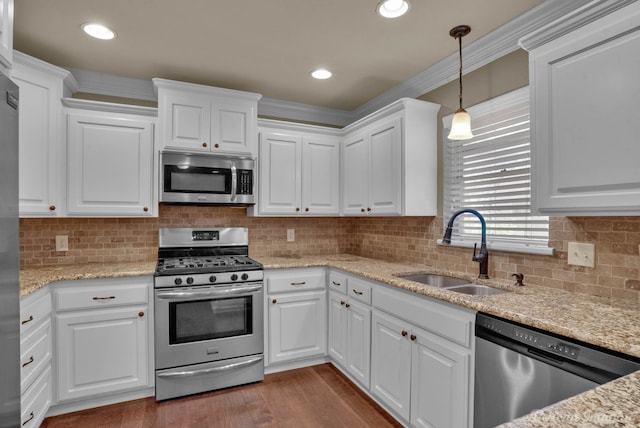 kitchen featuring sink, white cabinets, appliances with stainless steel finishes, hardwood / wood-style floors, and ornamental molding