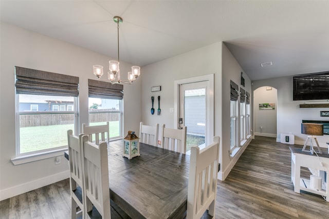 dining area featuring a notable chandelier, a healthy amount of sunlight, and dark hardwood / wood-style flooring