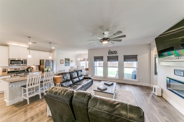 living room with ceiling fan and light wood-type flooring