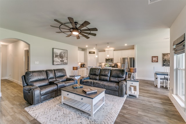 living room featuring light hardwood / wood-style flooring, ceiling fan, and plenty of natural light