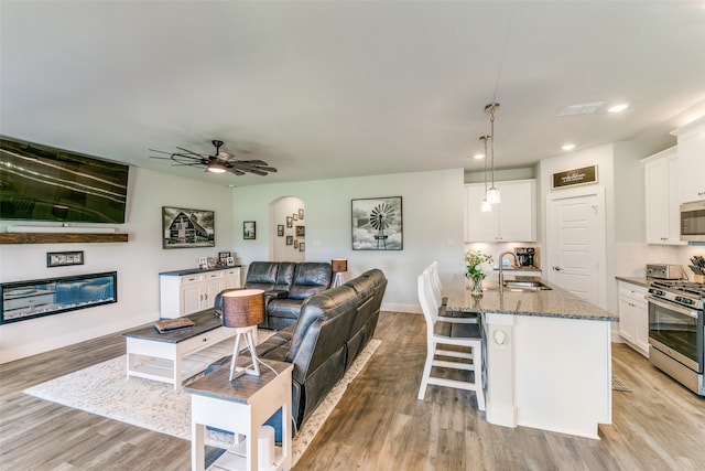 living room featuring light wood-type flooring, sink, and ceiling fan