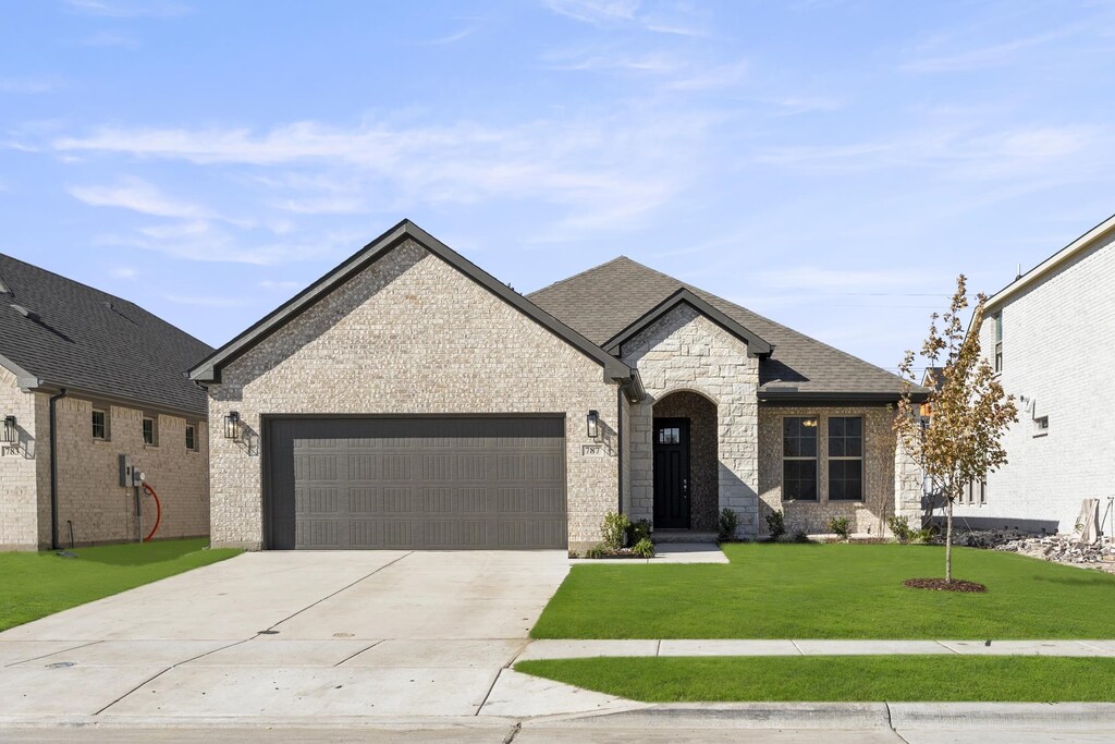 french country style house featuring a front lawn and a garage