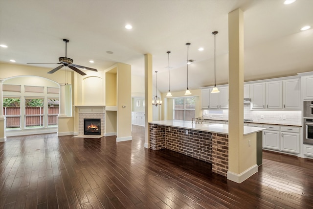 kitchen featuring ceiling fan, hanging light fixtures, a brick fireplace, and dark hardwood / wood-style floors