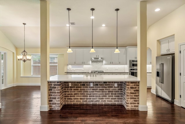 kitchen featuring appliances with stainless steel finishes, hanging light fixtures, and dark hardwood / wood-style flooring