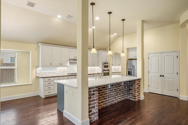 kitchen with appliances with stainless steel finishes, pendant lighting, a large island, and dark hardwood / wood-style floors