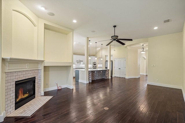 unfurnished living room with ceiling fan, a brick fireplace, and dark hardwood / wood-style flooring