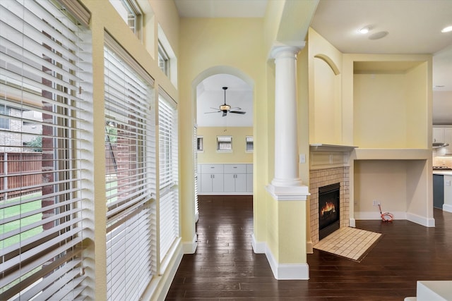 hall featuring ornate columns, a healthy amount of sunlight, and dark hardwood / wood-style flooring