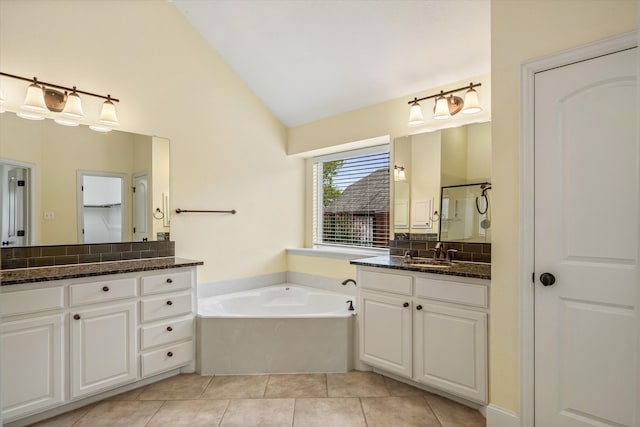 bathroom with vaulted ceiling, tasteful backsplash, a bathing tub, vanity, and tile patterned floors