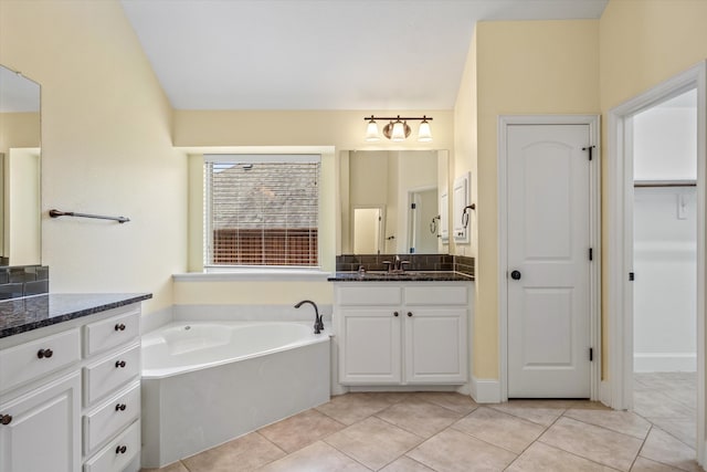 bathroom with a tub to relax in, tile patterned flooring, and vanity