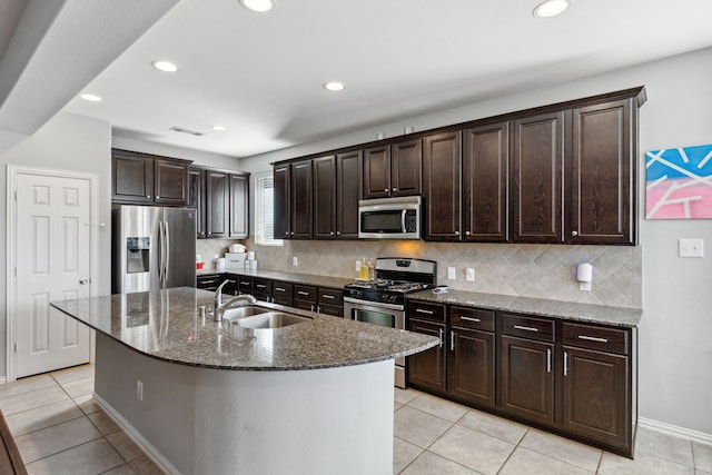 kitchen with dark brown cabinets, an island with sink, appliances with stainless steel finishes, and sink