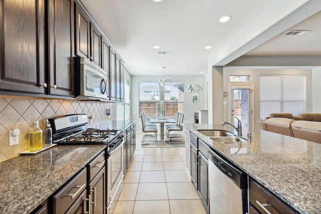 kitchen featuring dark brown cabinets, tasteful backsplash, sink, appliances with stainless steel finishes, and dark stone countertops