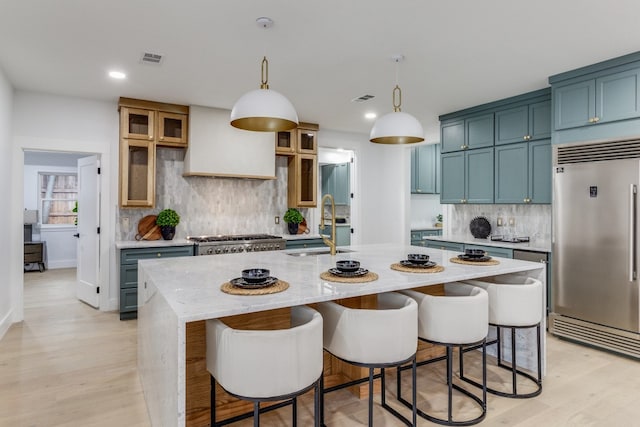 kitchen with stainless steel appliances, hanging light fixtures, tasteful backsplash, and a center island with sink