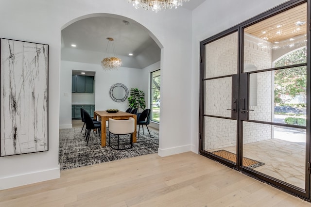 interior space with an inviting chandelier, light wood-type flooring, and a healthy amount of sunlight