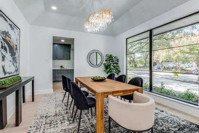 dining space with lofted ceiling, plenty of natural light, an inviting chandelier, and light wood-type flooring