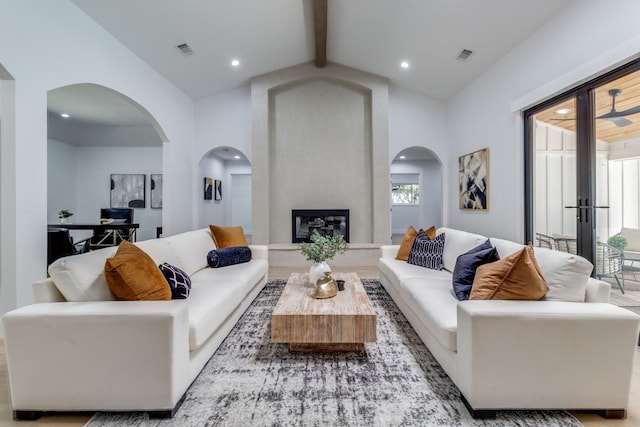 living room featuring beamed ceiling, high vaulted ceiling, and a large fireplace