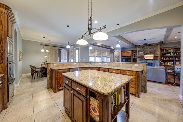 kitchen with hanging light fixtures, a fireplace, beam ceiling, ceiling fan, and a large island