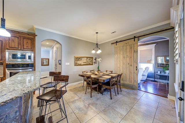 tiled dining area with ornamental molding, a chandelier, and a barn door