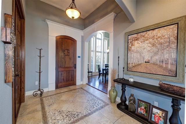 foyer entrance with light tile patterned flooring and crown molding