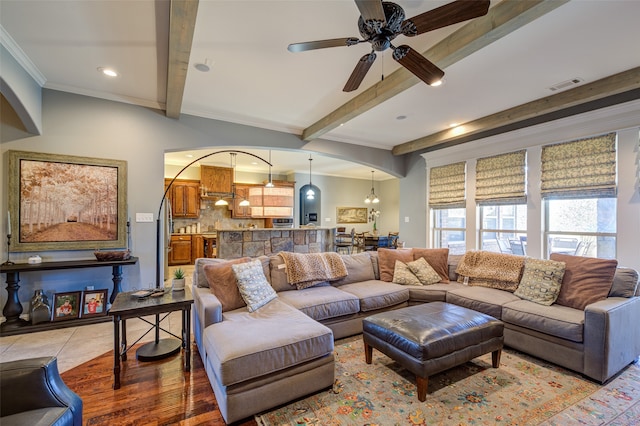 living room featuring ceiling fan with notable chandelier, beam ceiling, hardwood / wood-style flooring, and ornamental molding