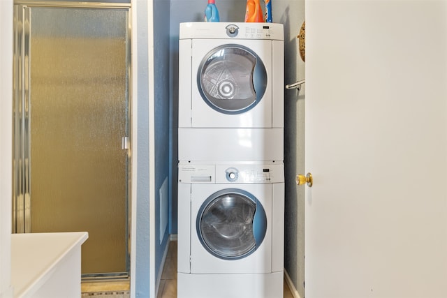 clothes washing area featuring stacked washer / dryer and light tile patterned flooring