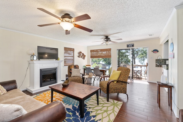 living room with a textured ceiling, ornamental molding, dark hardwood / wood-style flooring, and ceiling fan