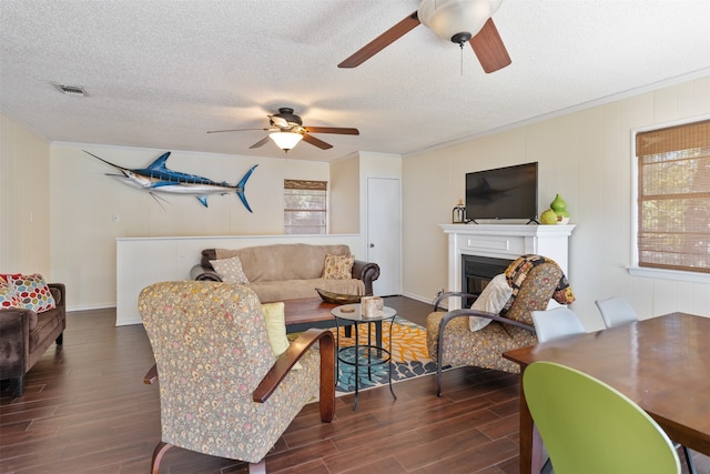 living room featuring ceiling fan, a textured ceiling, crown molding, and dark wood-type flooring