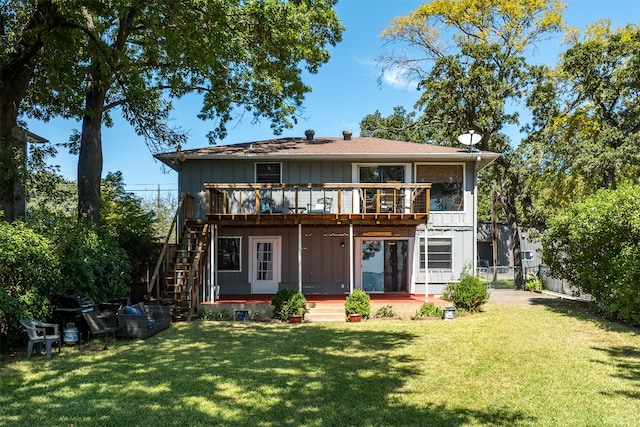 rear view of property featuring a balcony and a lawn