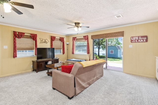 carpeted living room featuring a textured ceiling, ornamental molding, and ceiling fan