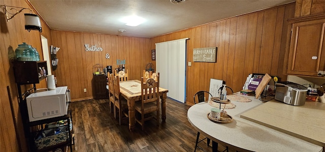 dining area featuring wooden walls and dark hardwood / wood-style floors