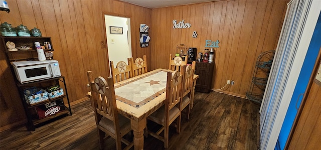 dining space with wooden walls and dark wood-type flooring