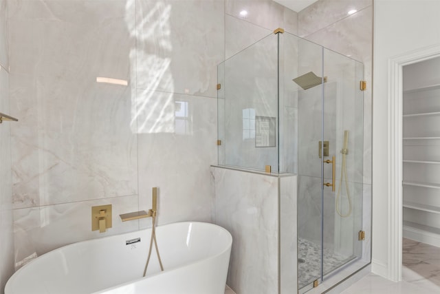 bathroom with tile walls and independent shower and bath