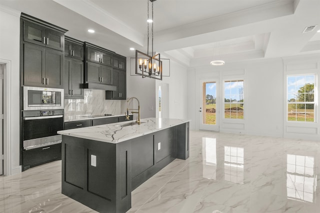 kitchen featuring pendant lighting, a kitchen island with sink, stainless steel appliances, and a tray ceiling