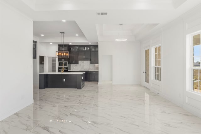 kitchen with a tray ceiling, a center island, hanging light fixtures, and backsplash