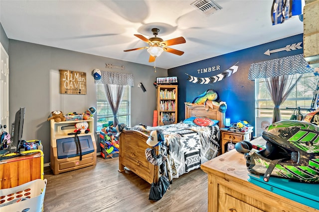 bedroom with ceiling fan, hardwood / wood-style flooring, and multiple windows