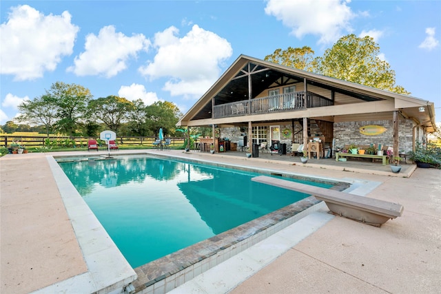 view of swimming pool with a diving board and a patio area