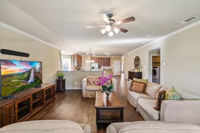 living room with ceiling fan with notable chandelier, washer / dryer, ornamental molding, and dark wood-type flooring