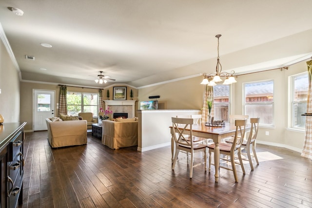 dining space with ceiling fan with notable chandelier, dark hardwood / wood-style floors, and vaulted ceiling