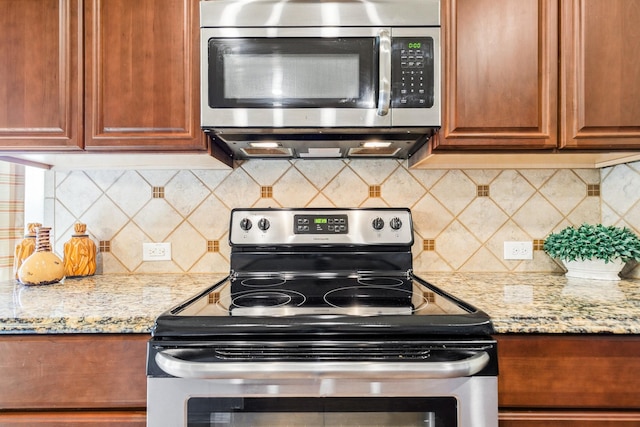 kitchen featuring decorative backsplash, stainless steel appliances, and light stone counters