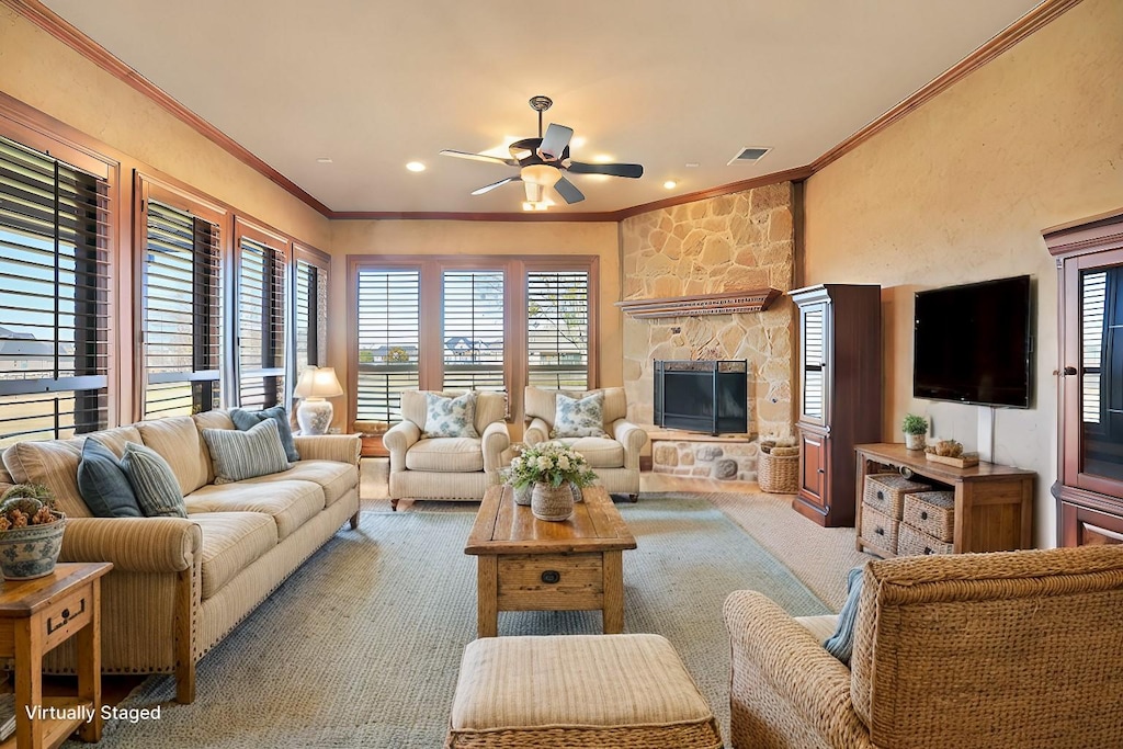 carpeted living room featuring a fireplace, ornamental molding, and ceiling fan