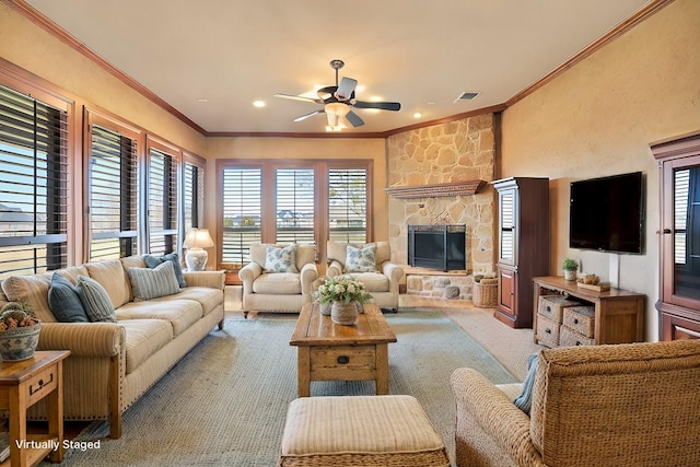 carpeted living room featuring a stone fireplace, ceiling fan, and ornamental molding