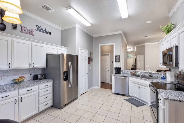 kitchen with ornamental molding, white cabinetry, stainless steel appliances, and light stone counters