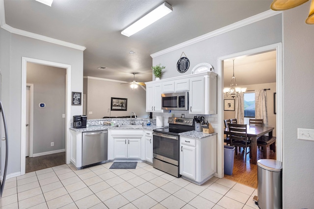 kitchen with appliances with stainless steel finishes, white cabinetry, ceiling fan with notable chandelier, ornamental molding, and sink