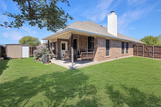 back of house featuring a shed, a lawn, and a patio